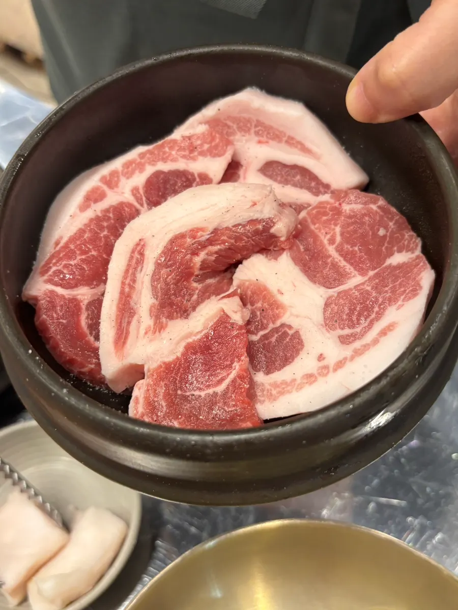 A piece of teukmokssal dipped in basil