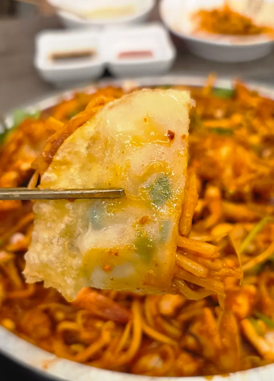 납작만두에 해물찜을 올려 싸 먹는 모습