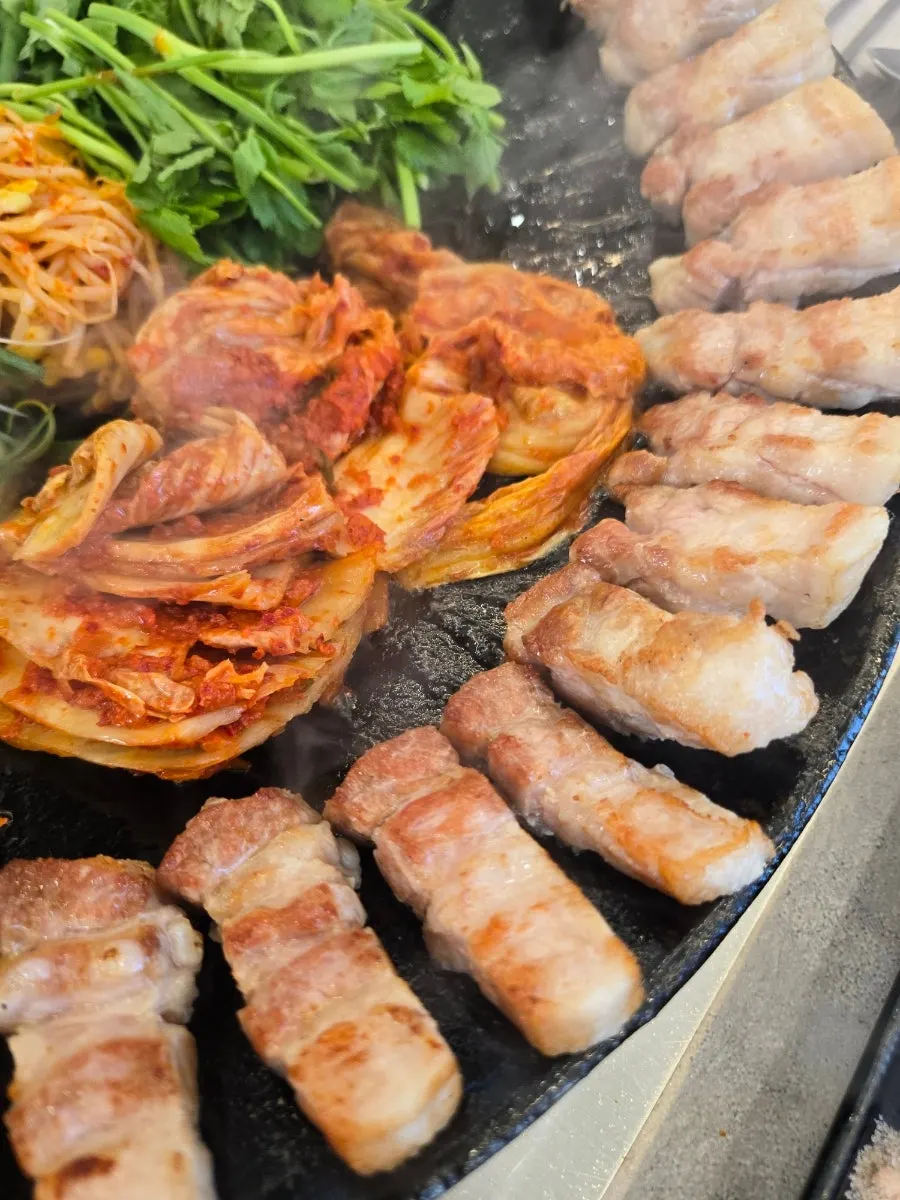 삼겹살 기름에 익어가는 김치와 미나리