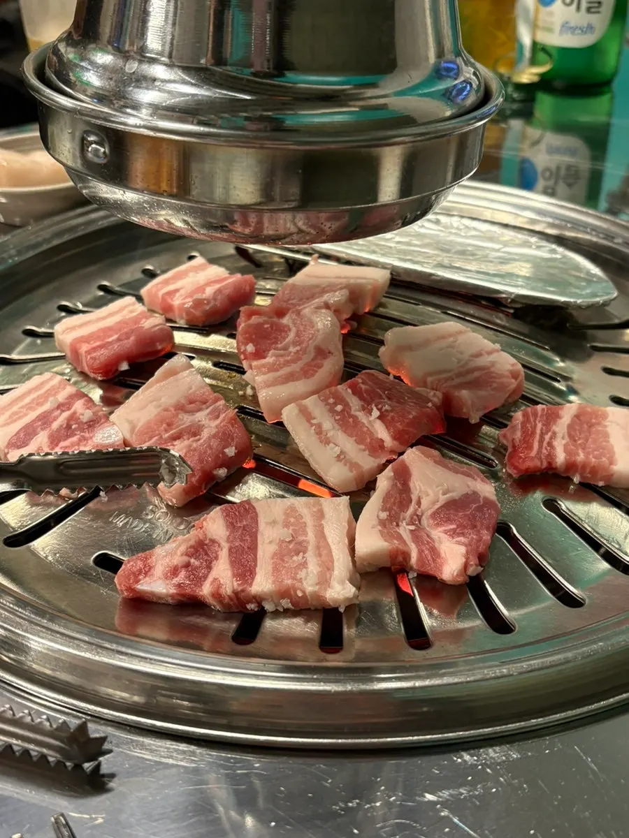 Pork belly grilling over charcoal