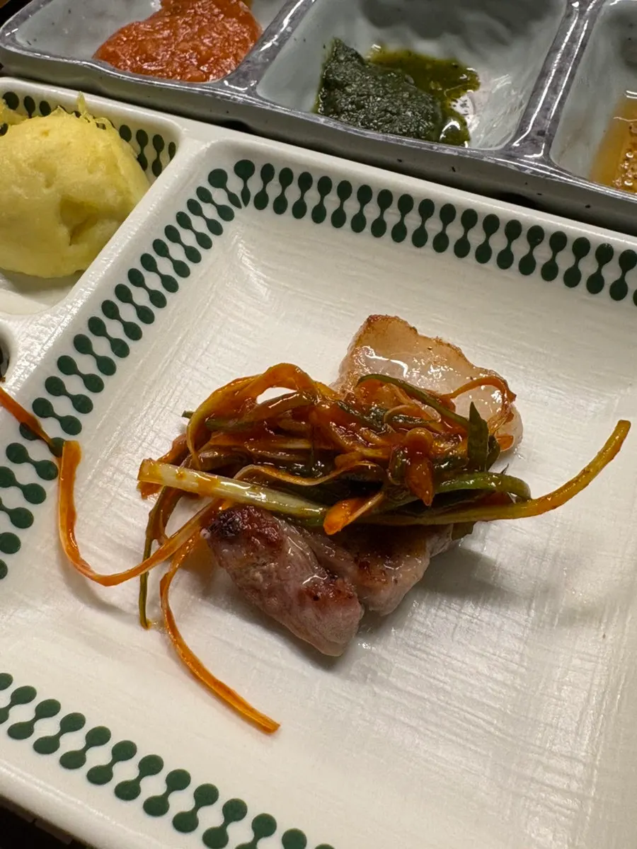 A piece of pork belly topped with scallion salad