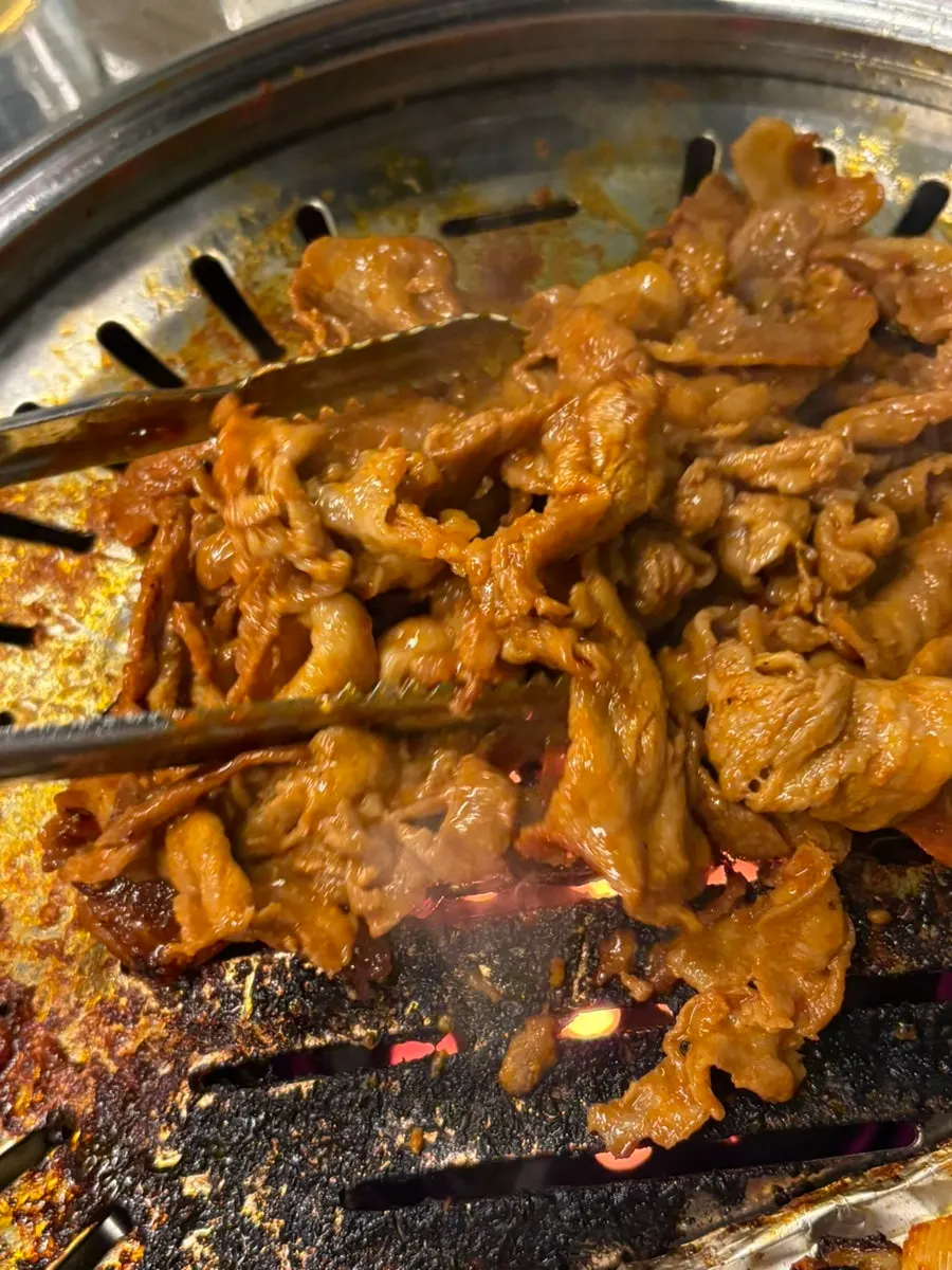 Gochujang bulgogi cooking over the charcoal grill