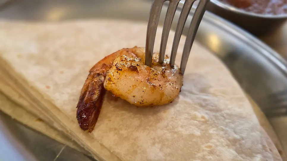 A bite of tortilla with more shrimp and vegetables