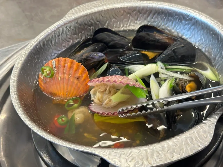 Clam soup broth topped with green onion and chili