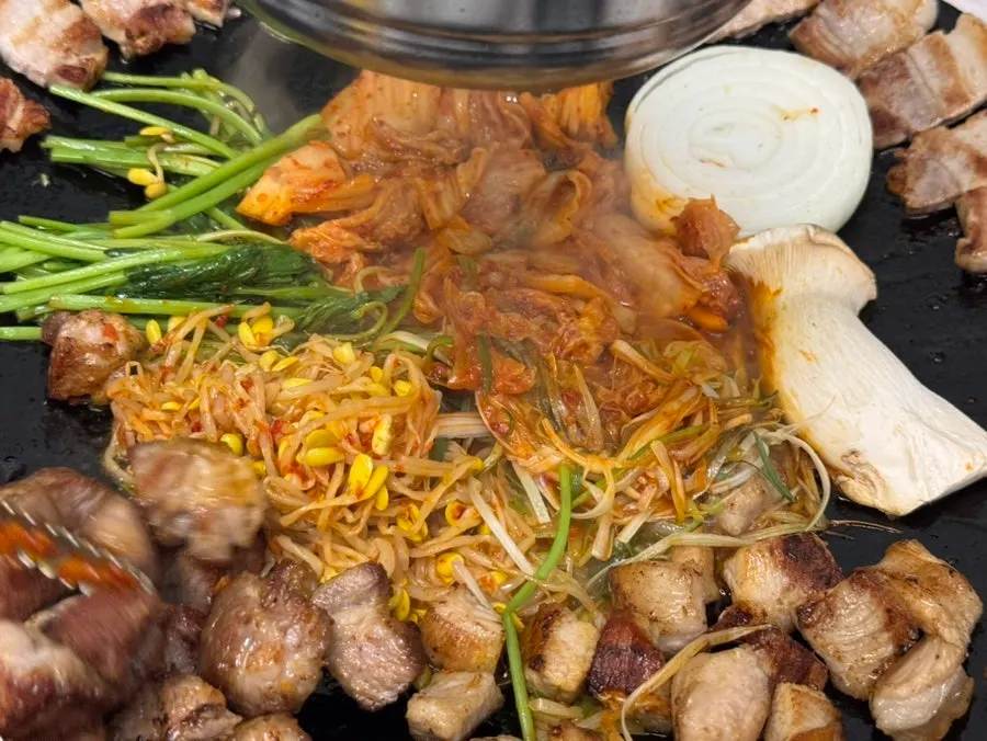 Grill topped with kimchi, minari, and bean sprouts