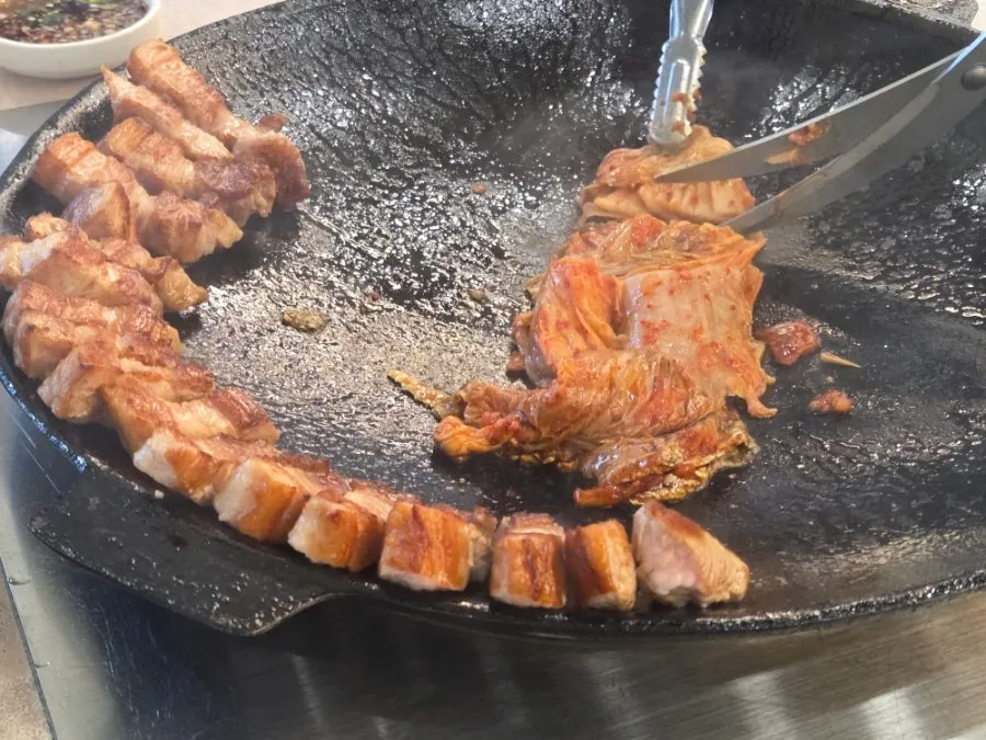 Pork belly and kimchi cooking on the grill