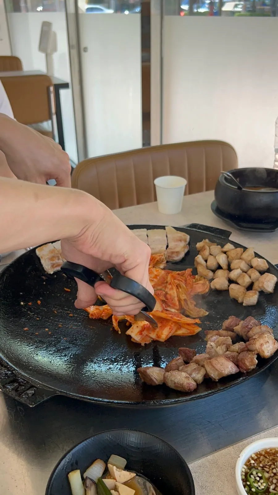 Staff member grilling meat on the pot lid