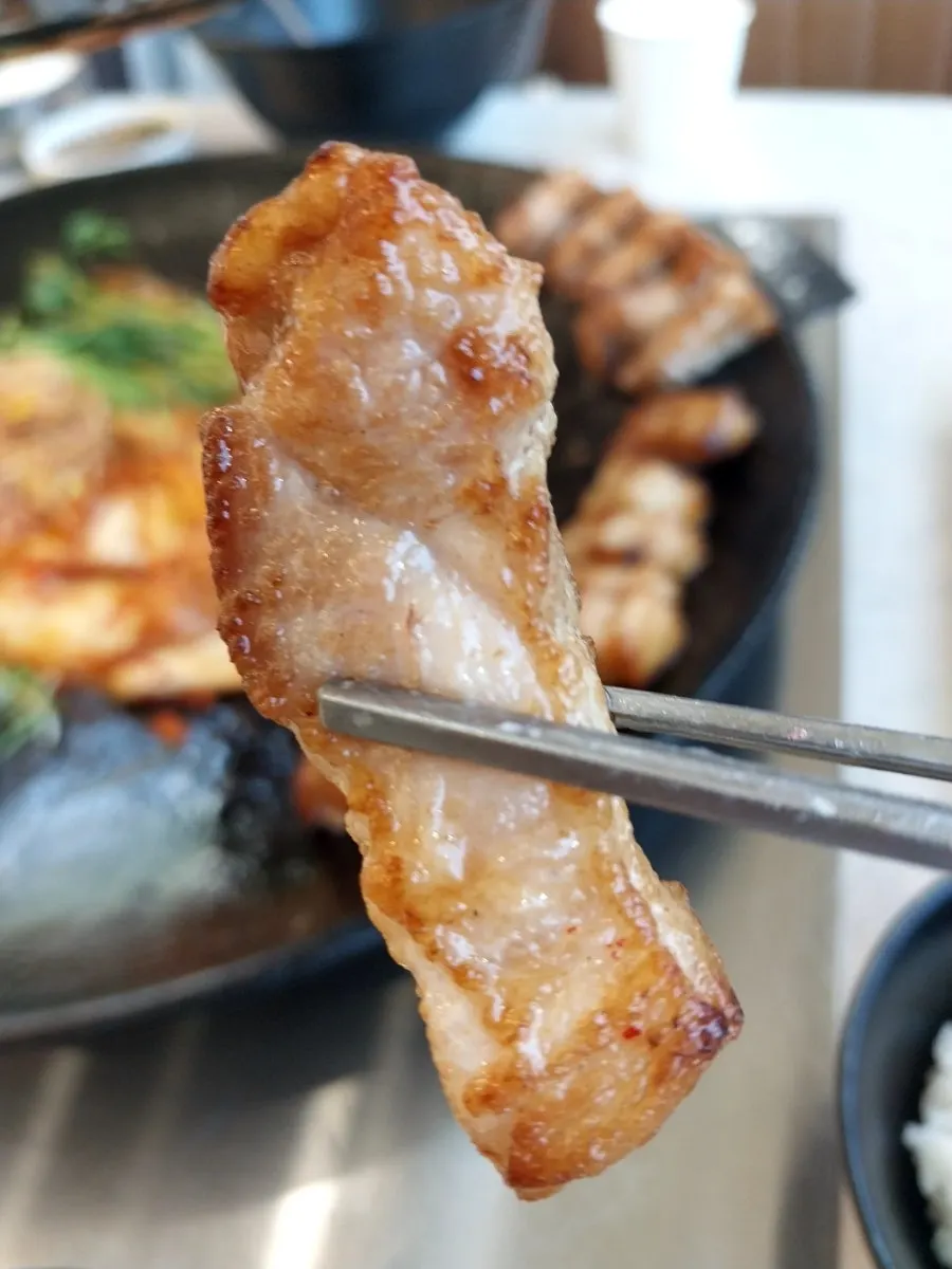 A piece of pork belly picked up with chopsticks