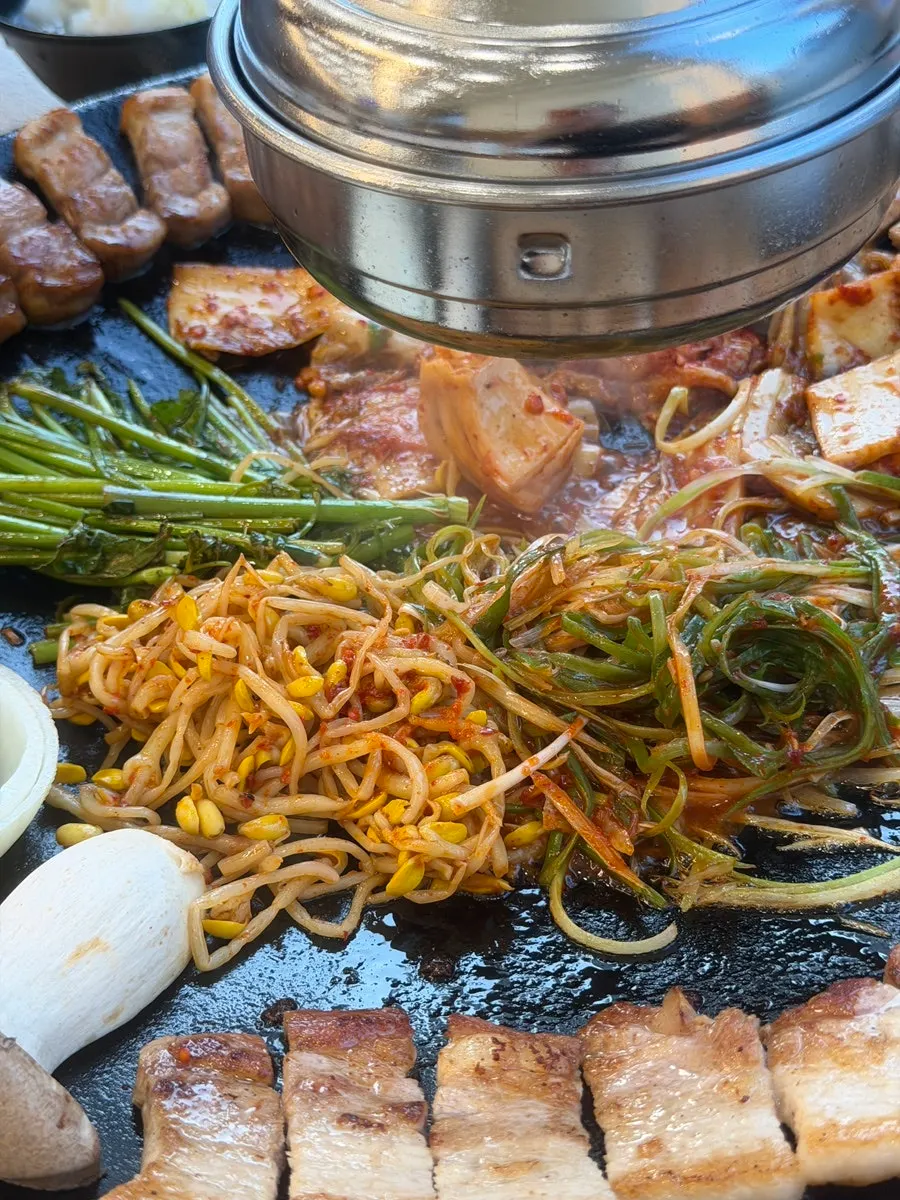 삼겹살 기름에 김치와 파채를 함께 굽는 솥뚜껑