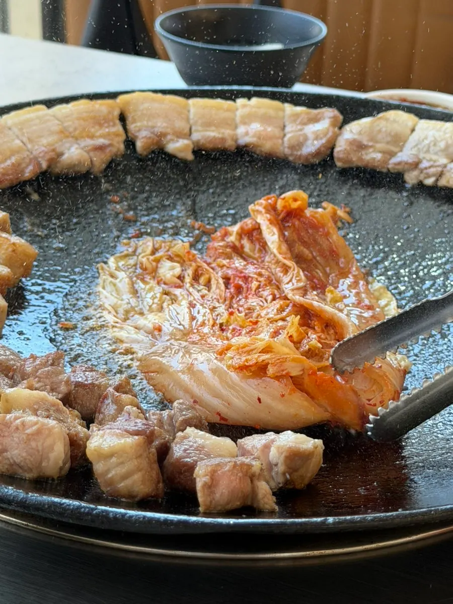 기름이 고이는 솥뚜껑 불판 위 김치구이