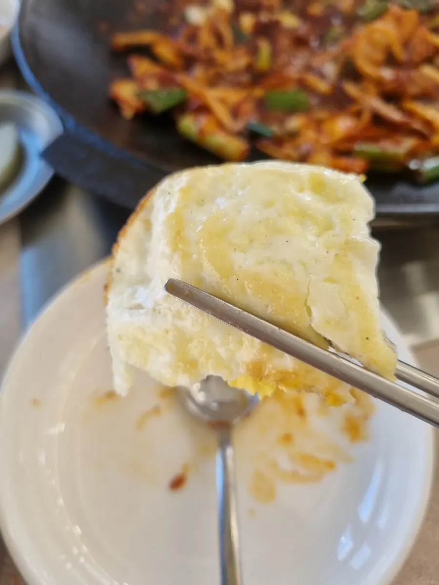 A spoonful of stir-fry eaten with fried egg