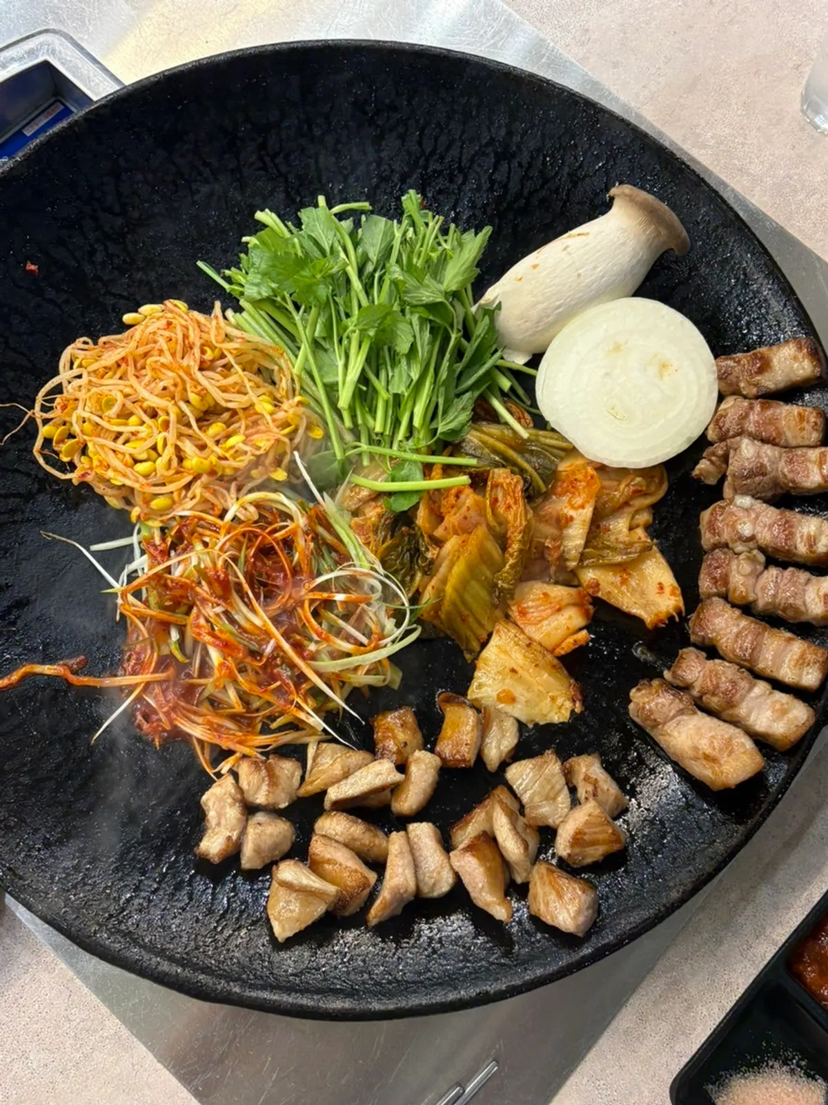 Hot pot lid pork belly topped with kimchi and minari