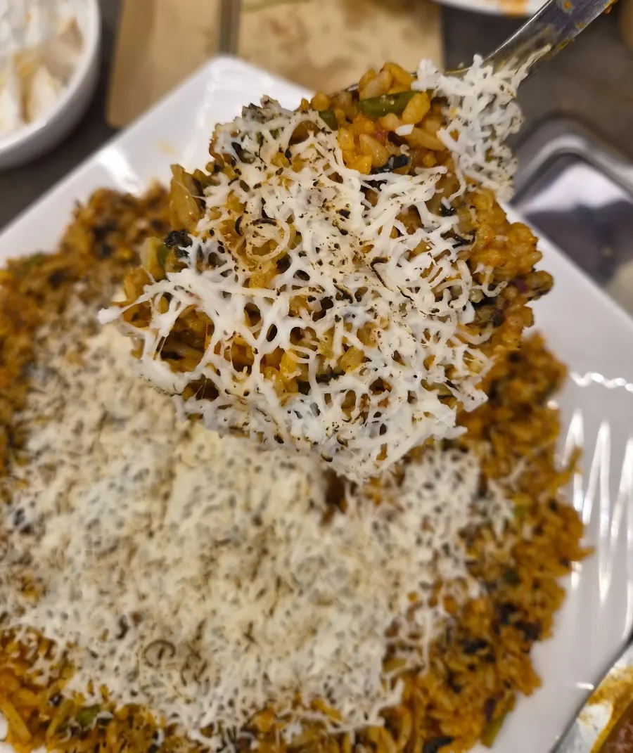 A spoonful of fried rice with seaweed flakes and cheese