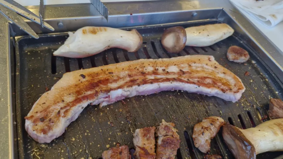 A large pan filled with thick pork belly and king oyster mushrooms