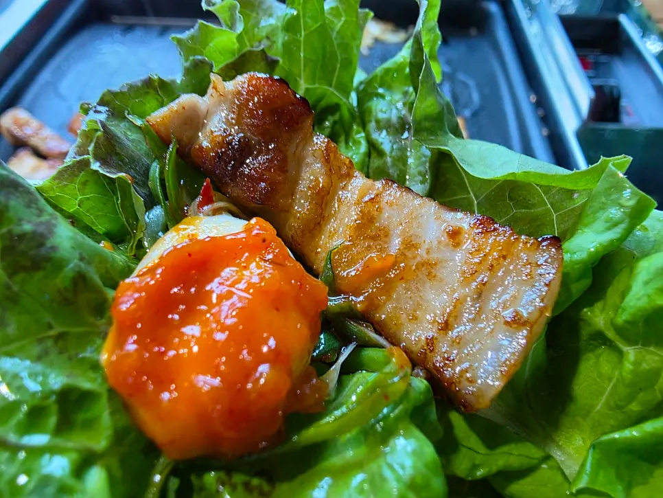 Pork belly cooking alongside enoki mushrooms