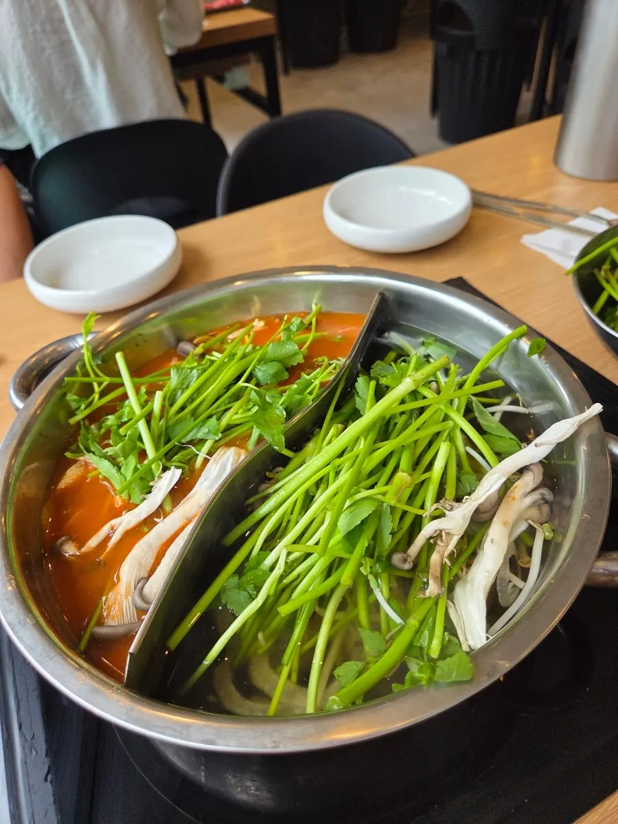 Adding meat to the boiling half-and-half broth pot