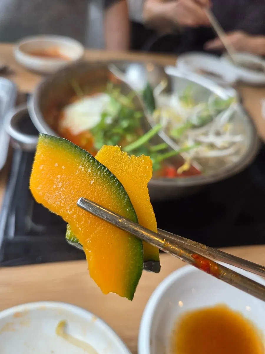 Plate of cooked meat and minari lifted from the pot