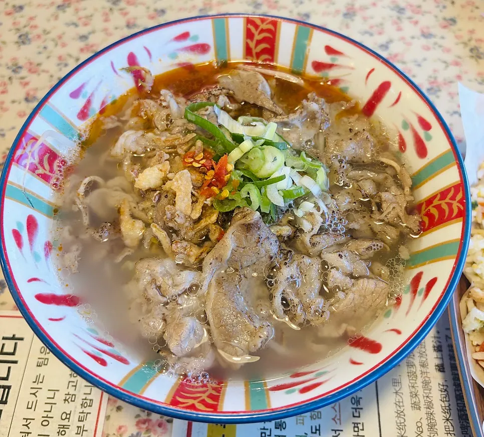 Thick noodles and morning glory lifted from the bowl
