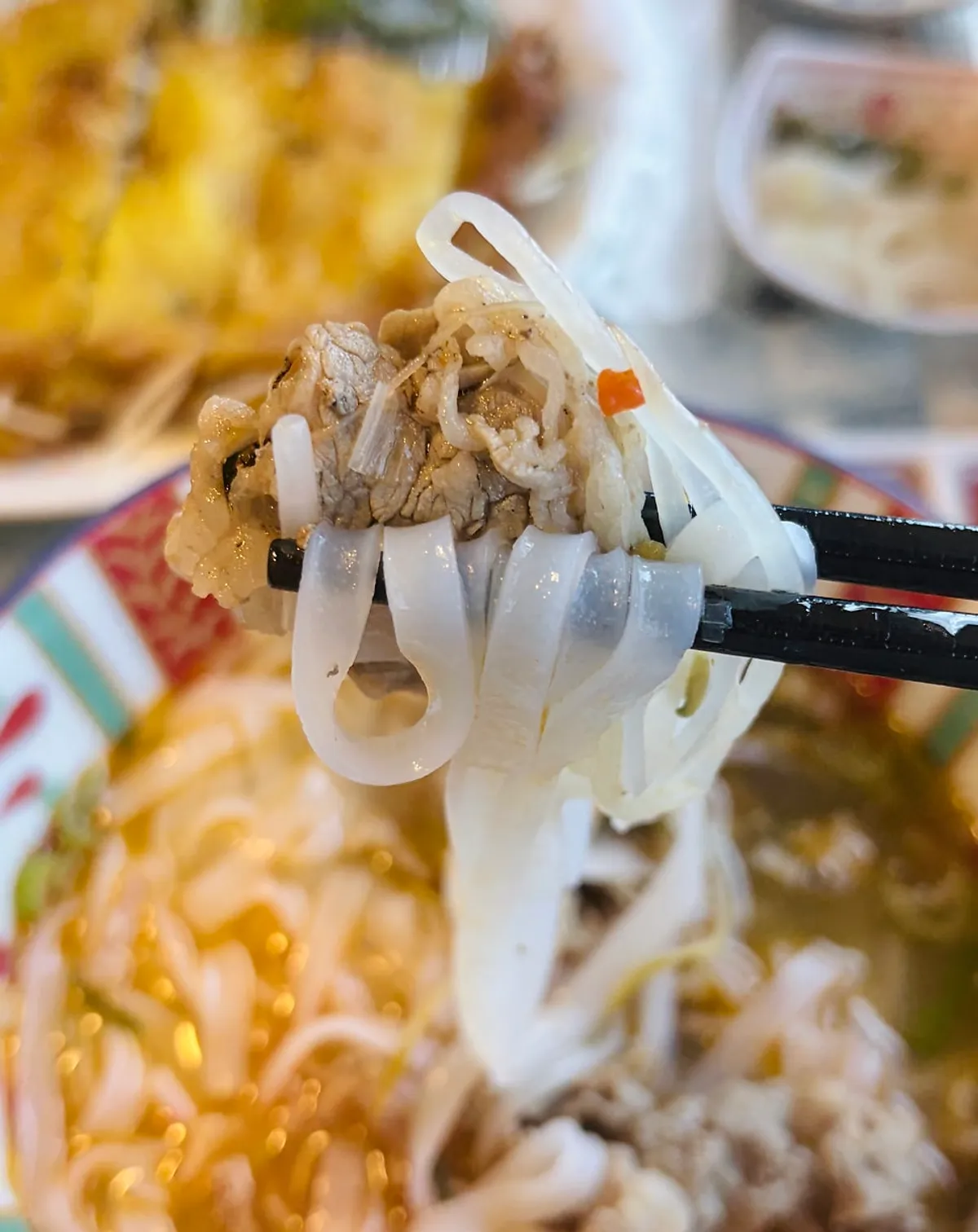 Lifting a bite of smoky beef pho noodles