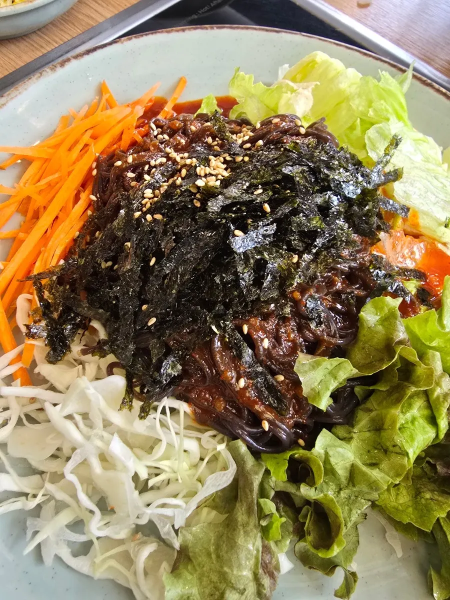 Mak guksu topped with vegetables and seaweed flakes