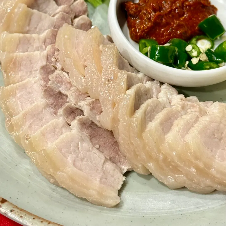Half-eaten plate of bossam with a soju glass