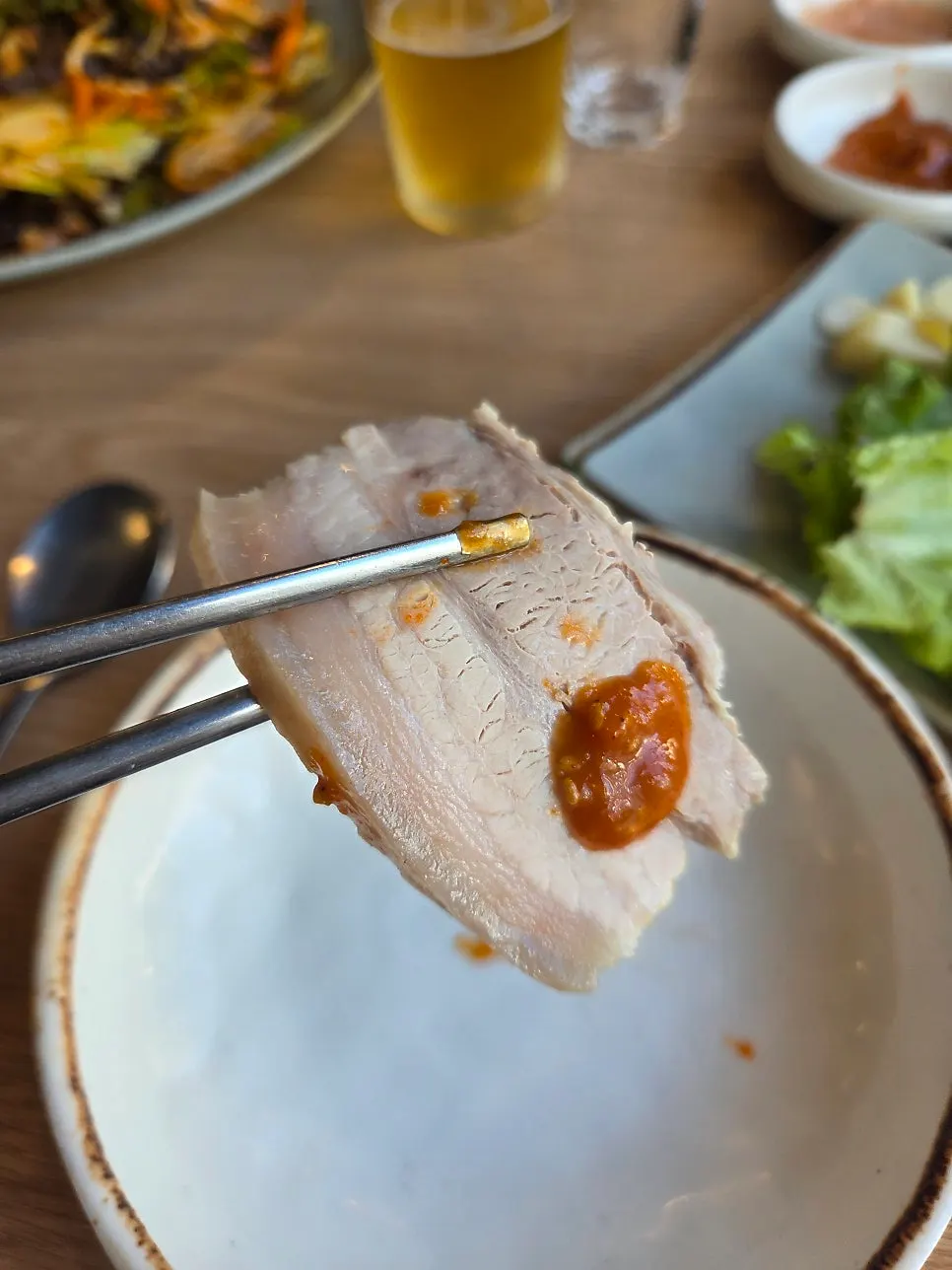 A piece of ohgyeop bossam dipped in ssamjang