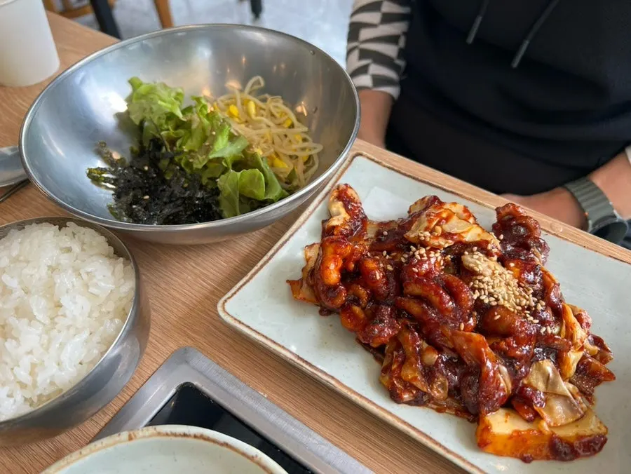 A piece of bossam topped with kimchi and side dishes