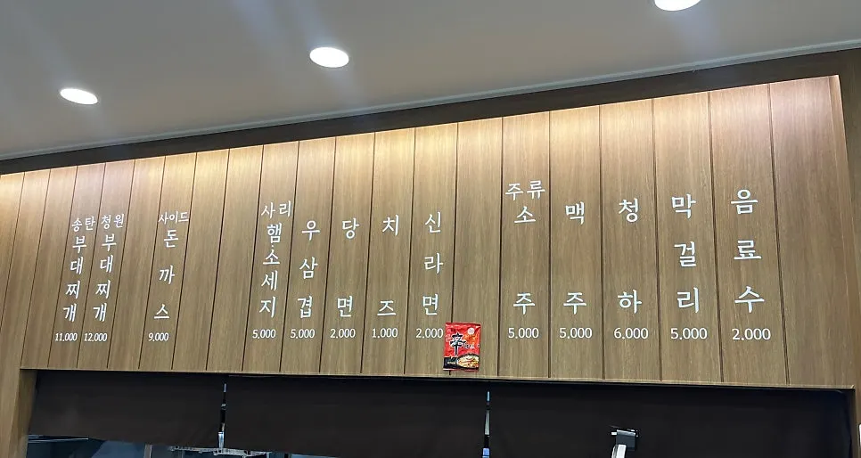 Menu board listing budae-jjigae, add-ins, and drinks
