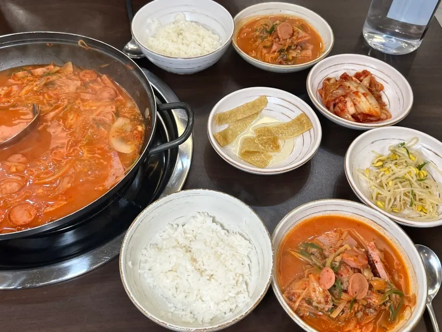 A ladleful of budae-jjigae scooped up with ham and sausage