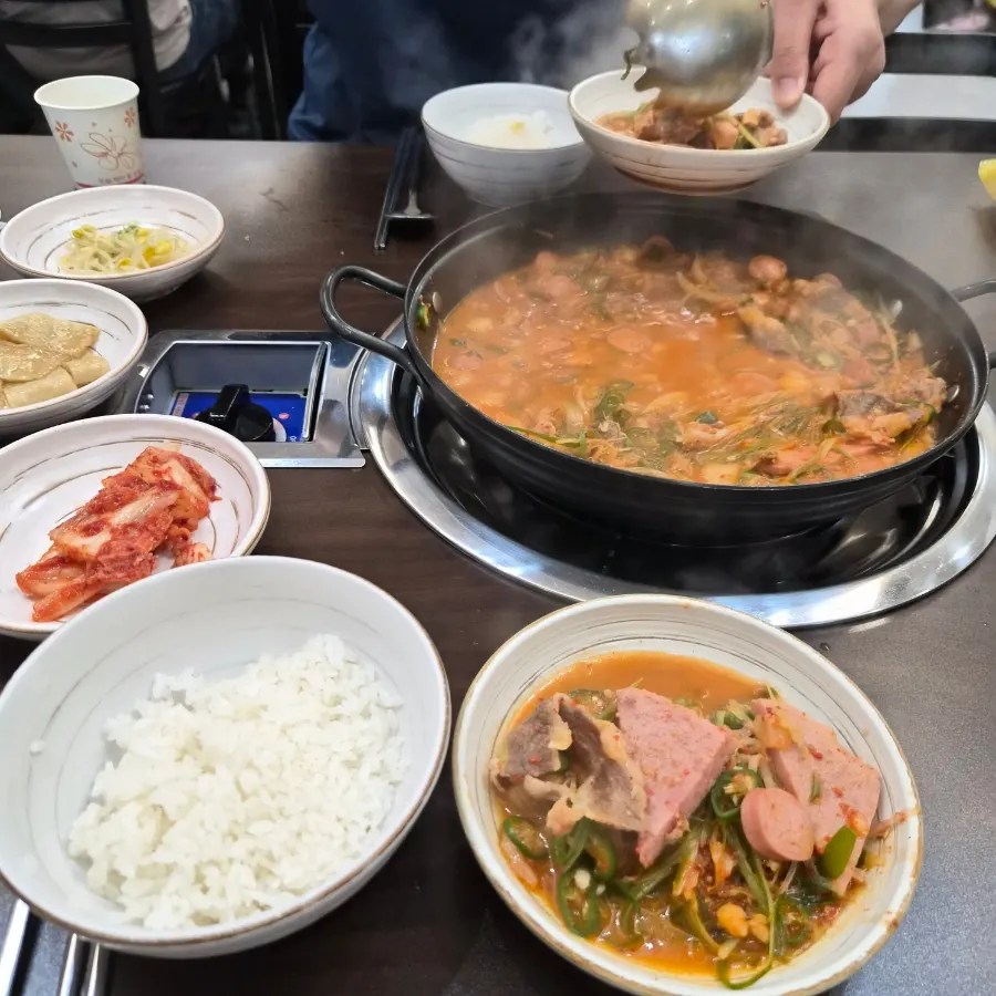 Full table spread of white rice, budae-jjigae, and egg roll