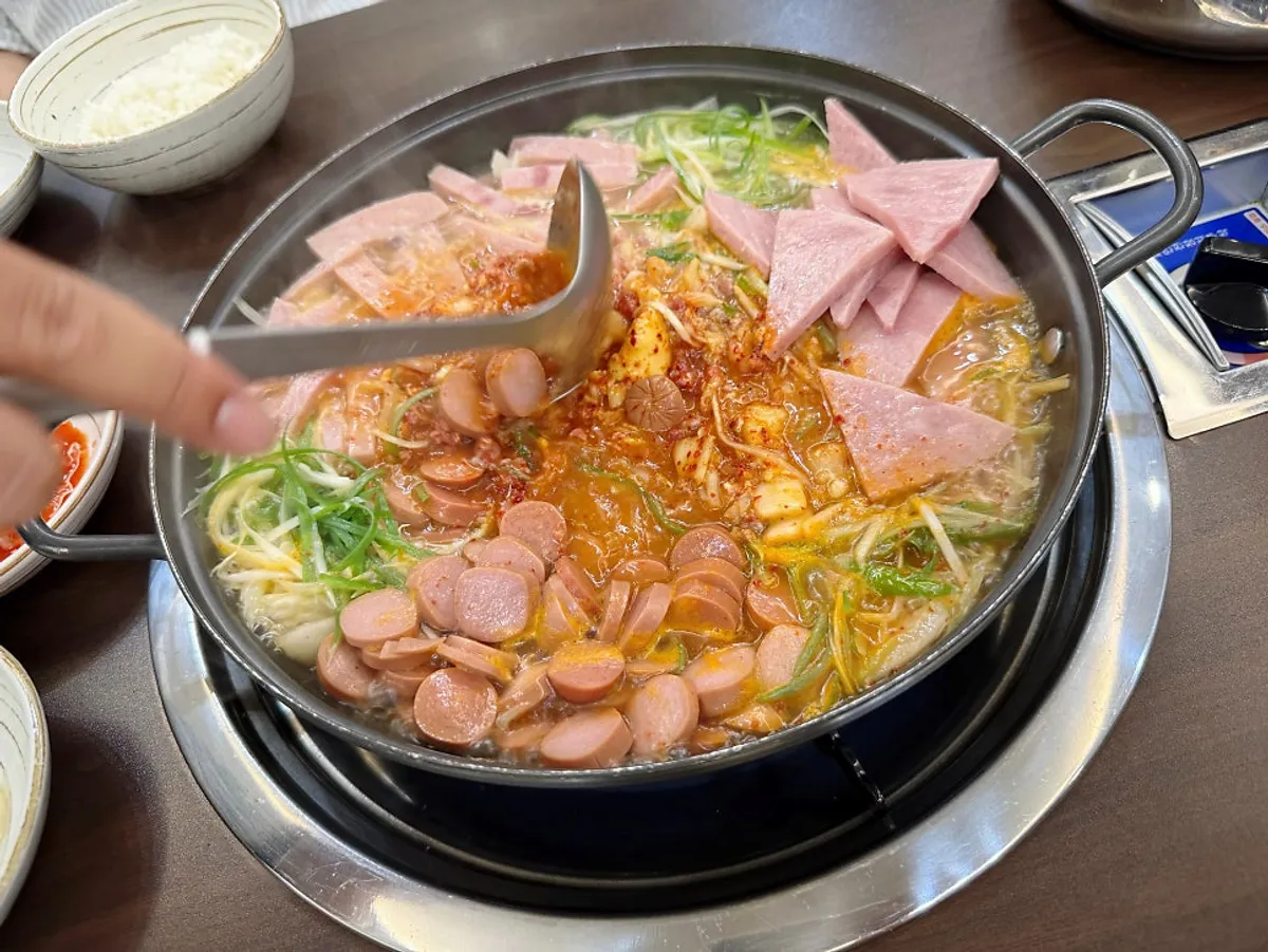 A pot of Songtan budae-jjigae generously loaded with ham and sausage