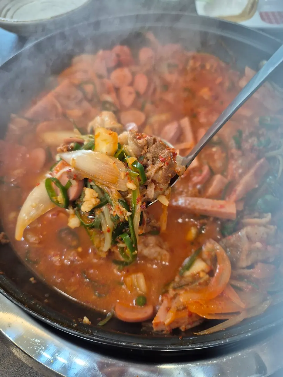 Bubbling beef brisket budae-jjigae broth with ham
