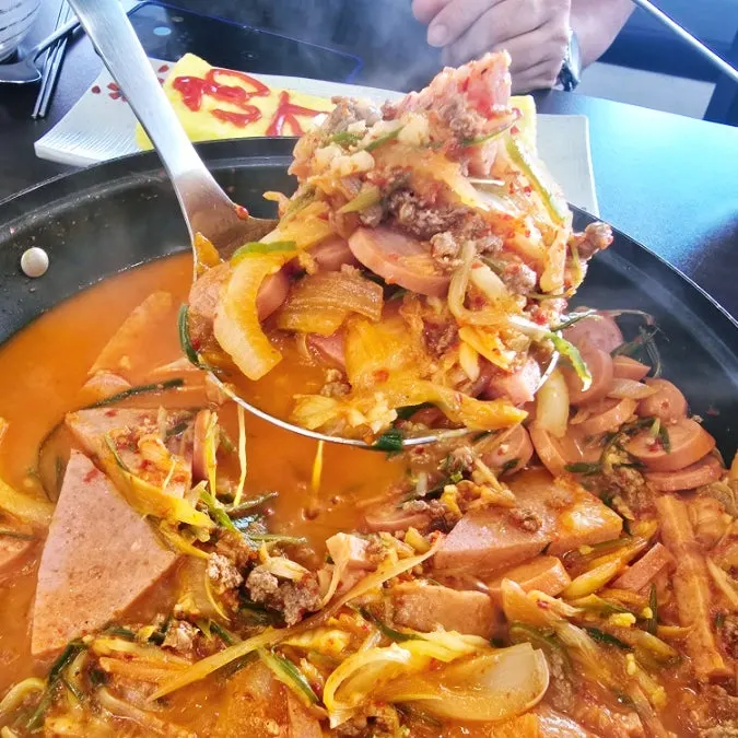 A ladleful of fully cooked Songtan budae-jjigae