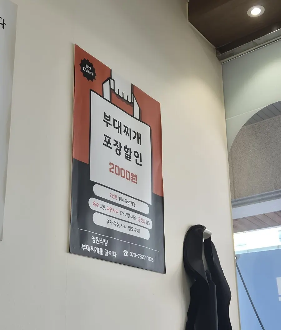 Wall sign advertising a ₩2,000 discount on takeout budae-jjigae