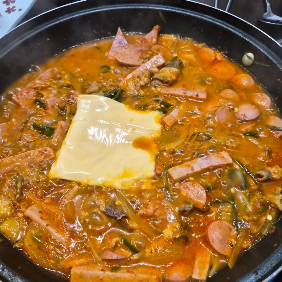 A ladleful of spicy broth with beef brisket from the budae-jjigae