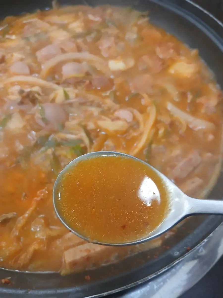 A spoonful of Songtan budae-jjigae with its spicy broth