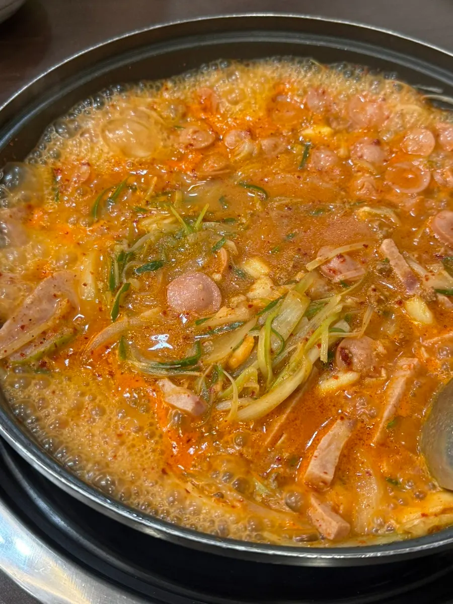 A pot of Songtan budae-jjigae topped with a slice of cheese