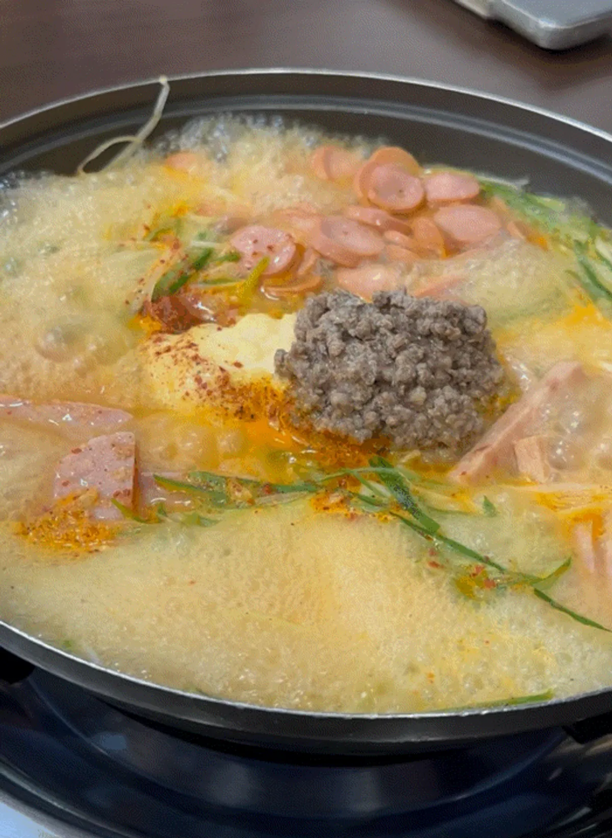 A spoonful of budae-jjigae with ham on top of rice