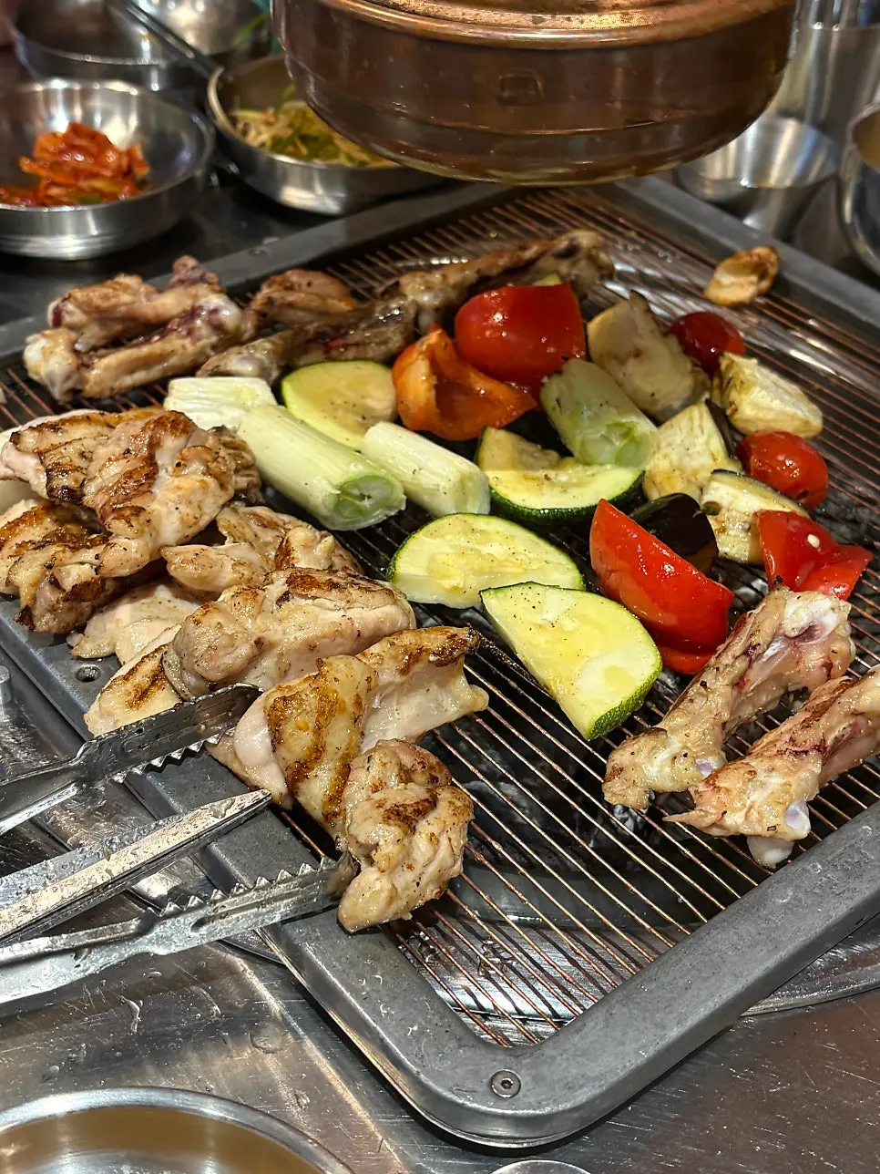 Vegetable skewer grilling alongside chicken galbi on the pan