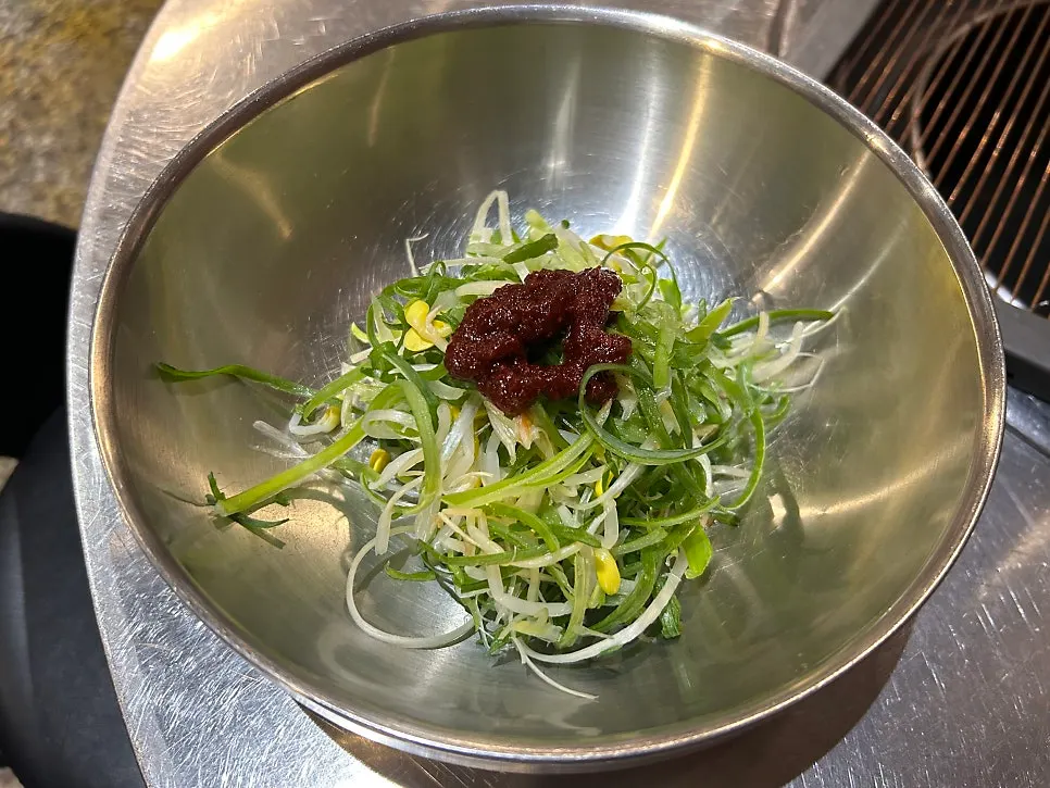Basic table setup with pickled radish, green onion kimchi, shredded green onion, fried gizzards, and doenjang stew