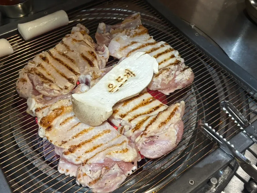 A staff member grilling charcoal chicken galbi on the grill