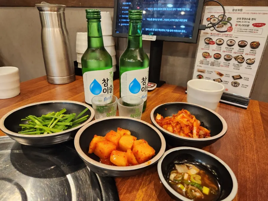 Chamisul soju and side dishes of kkakdugi, kimchi, chives, and salted shrimp