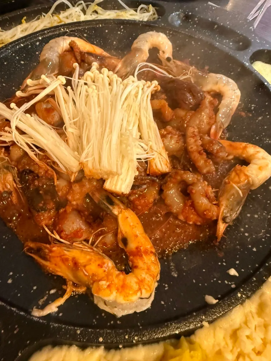 Jjukkumi and shrimp bubbling in seasoning as they cook