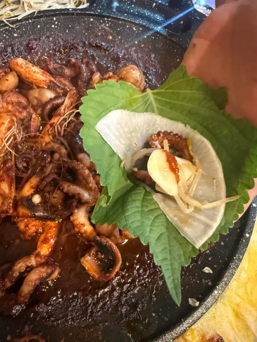 A perilla-leaf wrap with jjukkumi, bean sprouts, and garlic