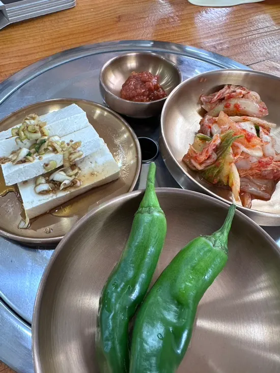 Side dish spread of kimchi, cucumber peppers, and soy-sauce tofu