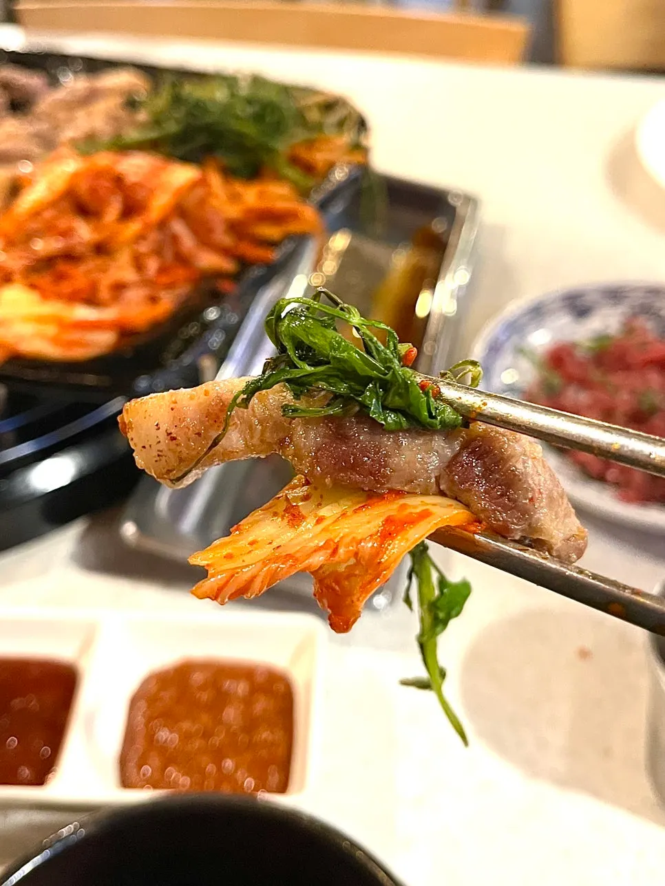 구운 김치와 미나리를 올린 삼겹살 한입