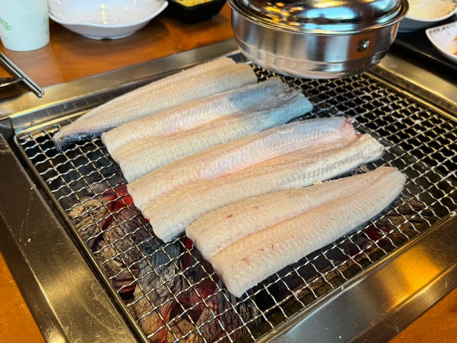 Staff member grilling golden-brown eel
