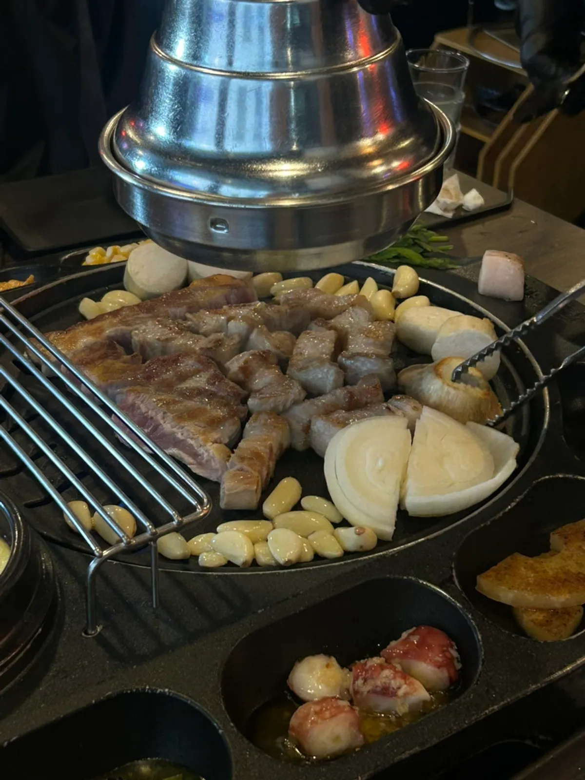 Mushrooms, onions, and garlic grilling alongside the pork belly