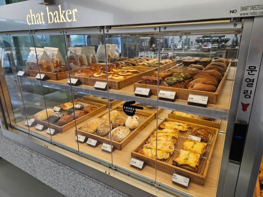 Automatic-door hygiene showcase displaying bread at Chat Baker