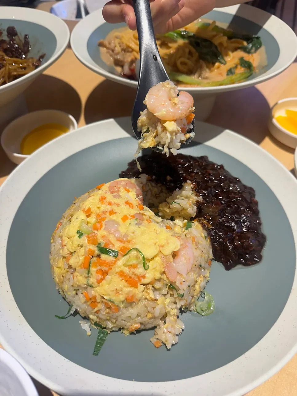 A spoonful of shrimp fried rice with jjajang sauce